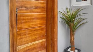 A wooden door with a modern design, a potted plant, and a window with a view. - 1 Bedroom Ensuite in a Shared House (Lekki)