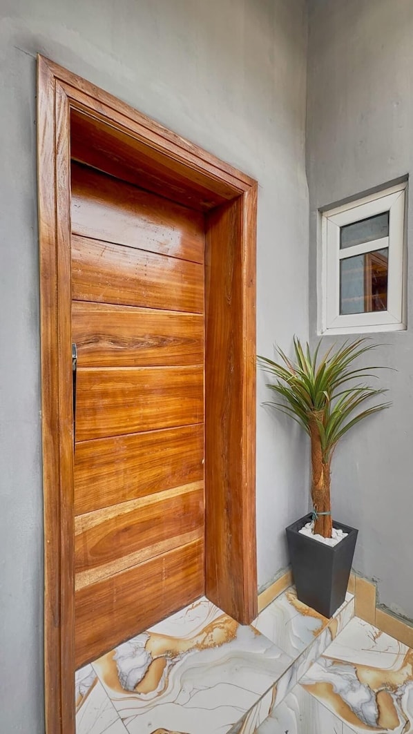 A wooden door with a modern design, a potted plant, and a window with a view. - 5 Bedrooms Einsuite House in Lekki Lagos Nigeria (Lekki)