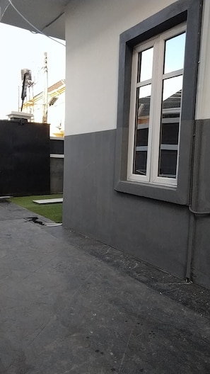 A building exterior with a large window, a concrete ground, and a visible construction crane in the background. - 5 Bedrooms Einsuite House in Lekki Lagos Nigeria (Lekki)
