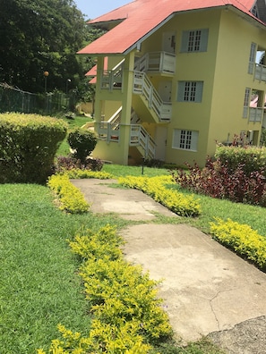 A yellow building with a red roof, surrounded by well-maintained gardens and a concrete pathway. - Endless Summer at Mystic Ridge (Ocho Rios)