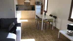Een ruimtelijk ingerichte leefruimte met kitchenette, eethoek en zithoek.