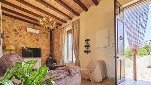 Una sala de estar con pared de piedra, un candelabro, un televisor y una planta grande.