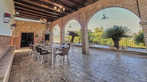Un patio al aire libre con suelo de piedra, un arco de ladrillo y una mesa con sillas.