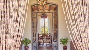 Un pasillo con una rústica puerta de madera, un candelabro y plantas en macetas.