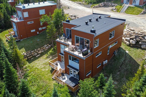 A modern multi-story building with a flat roof, large windows, and balconies. - Les Chalets Forêt (Petite-Riviere-Saint-Francois)
