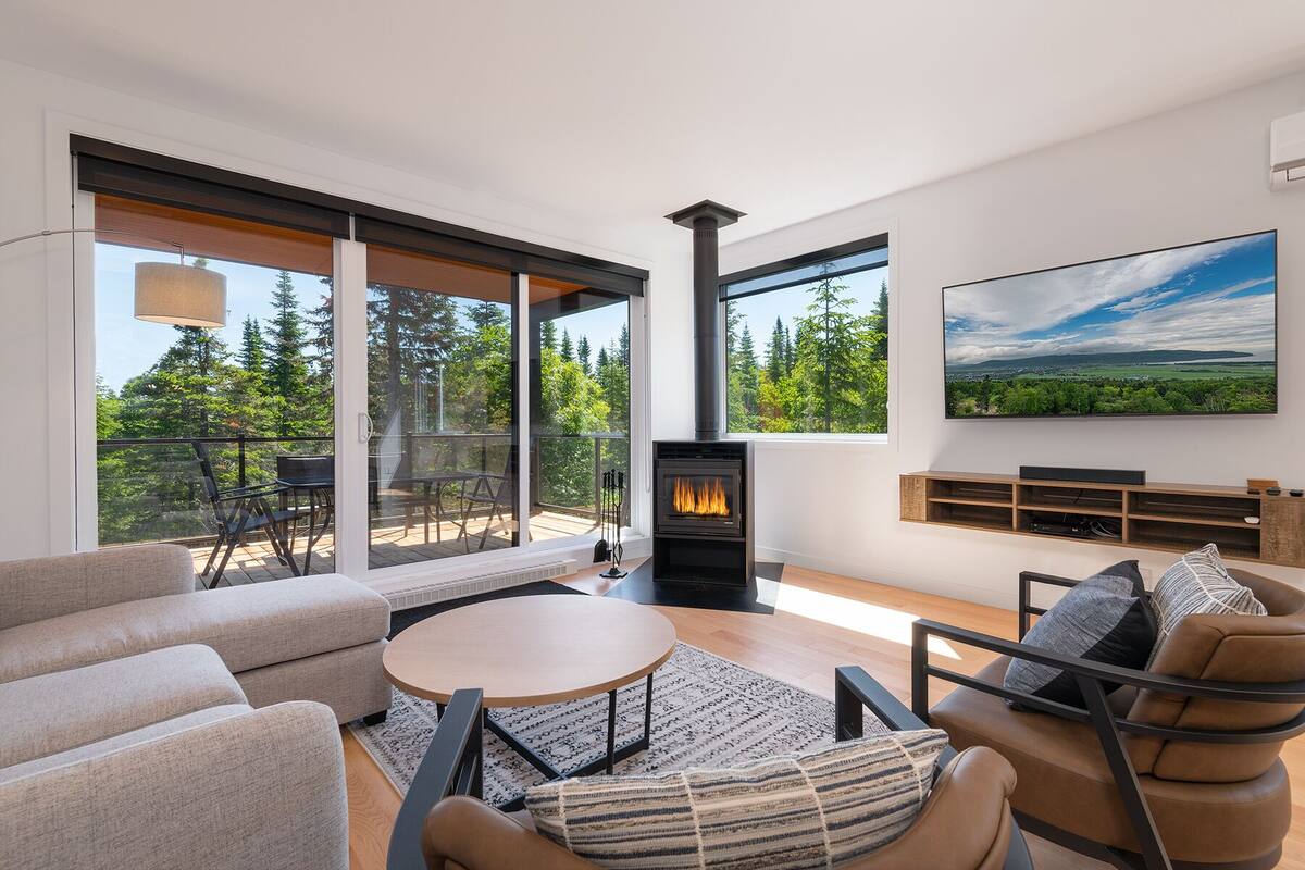 A modern living room with a fireplace, large windows, and a view of the outdoors.