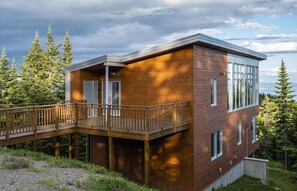 A modern two-story house with a wooden deck and large windows. - Les Chalets Forêt (Petite-Riviere-Saint-Francois)