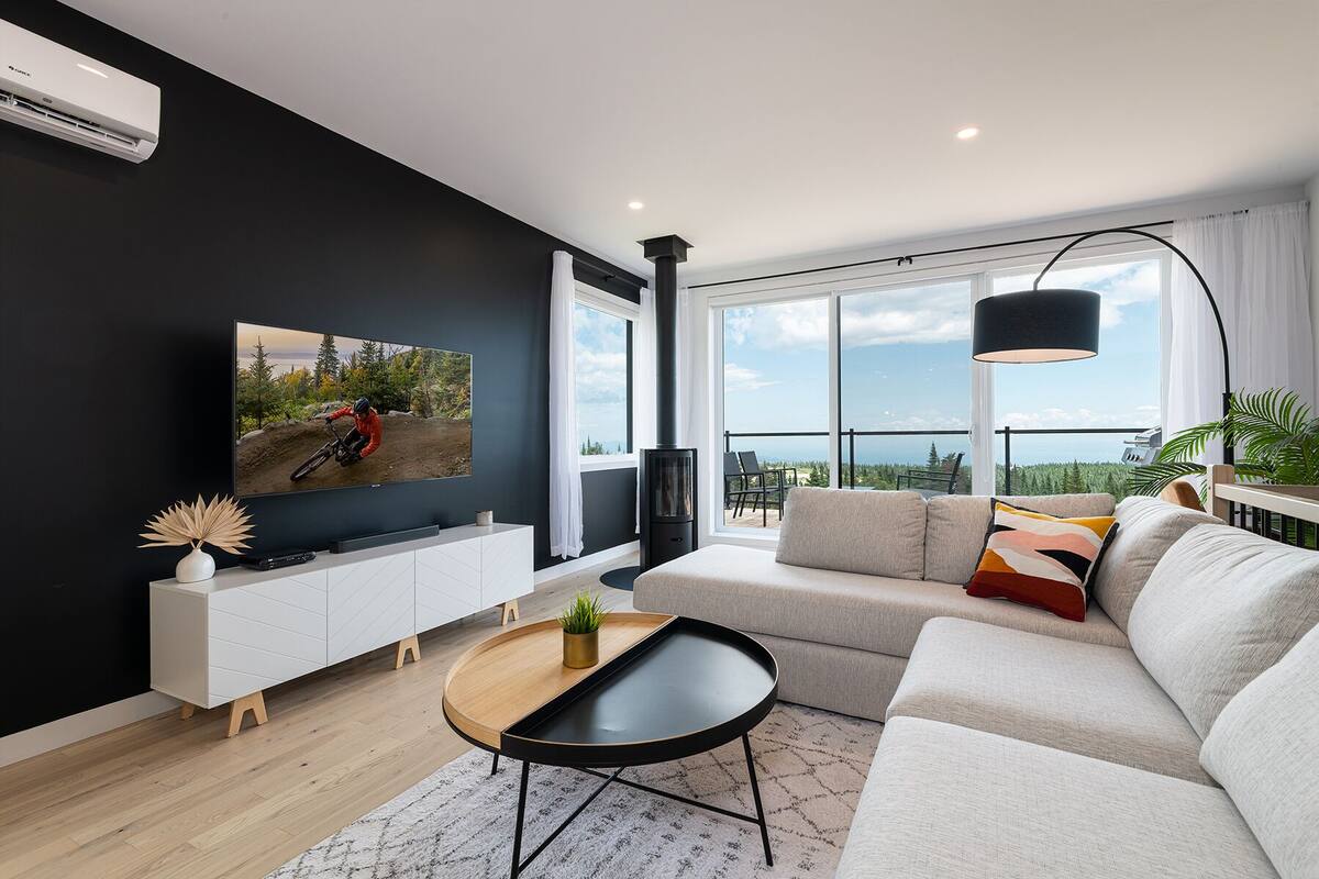 A modern living room with a large TV, a sofa, a coffee table, and a fireplace.