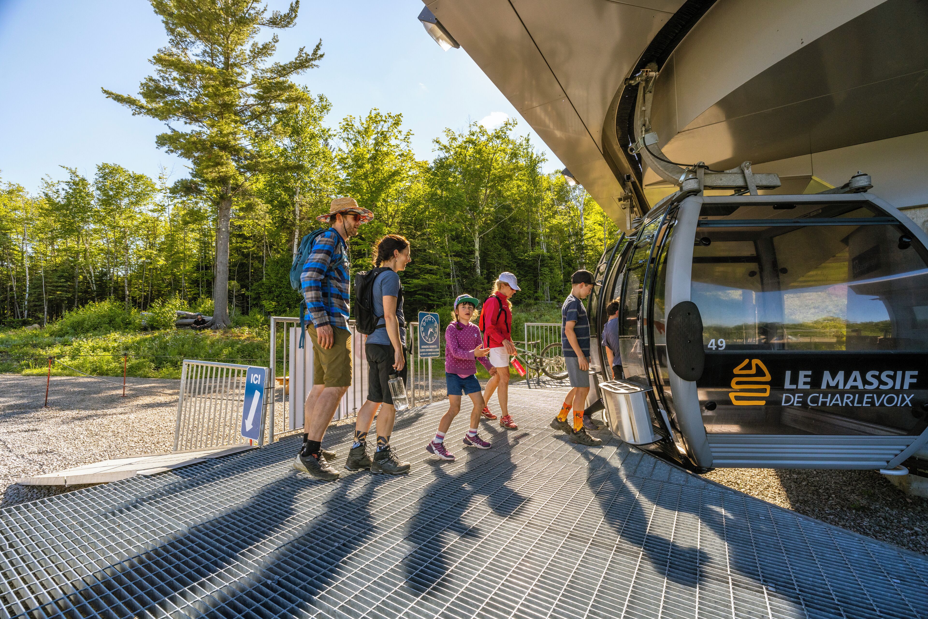 A group of people boarding a cable car with a sign reading "LE MASSIF DE CHARLEVOIX".