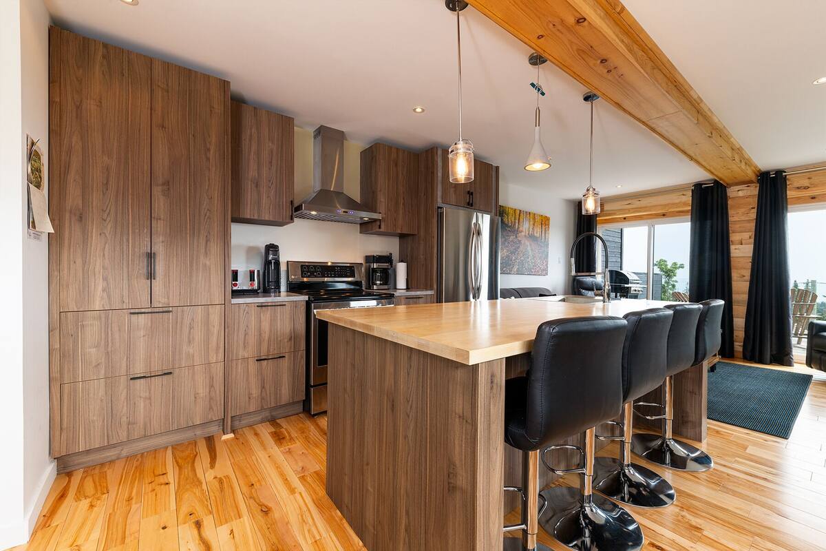 A modern kitchen with wooden cabinets, stainless steel appliances, and a central island with bar stools.