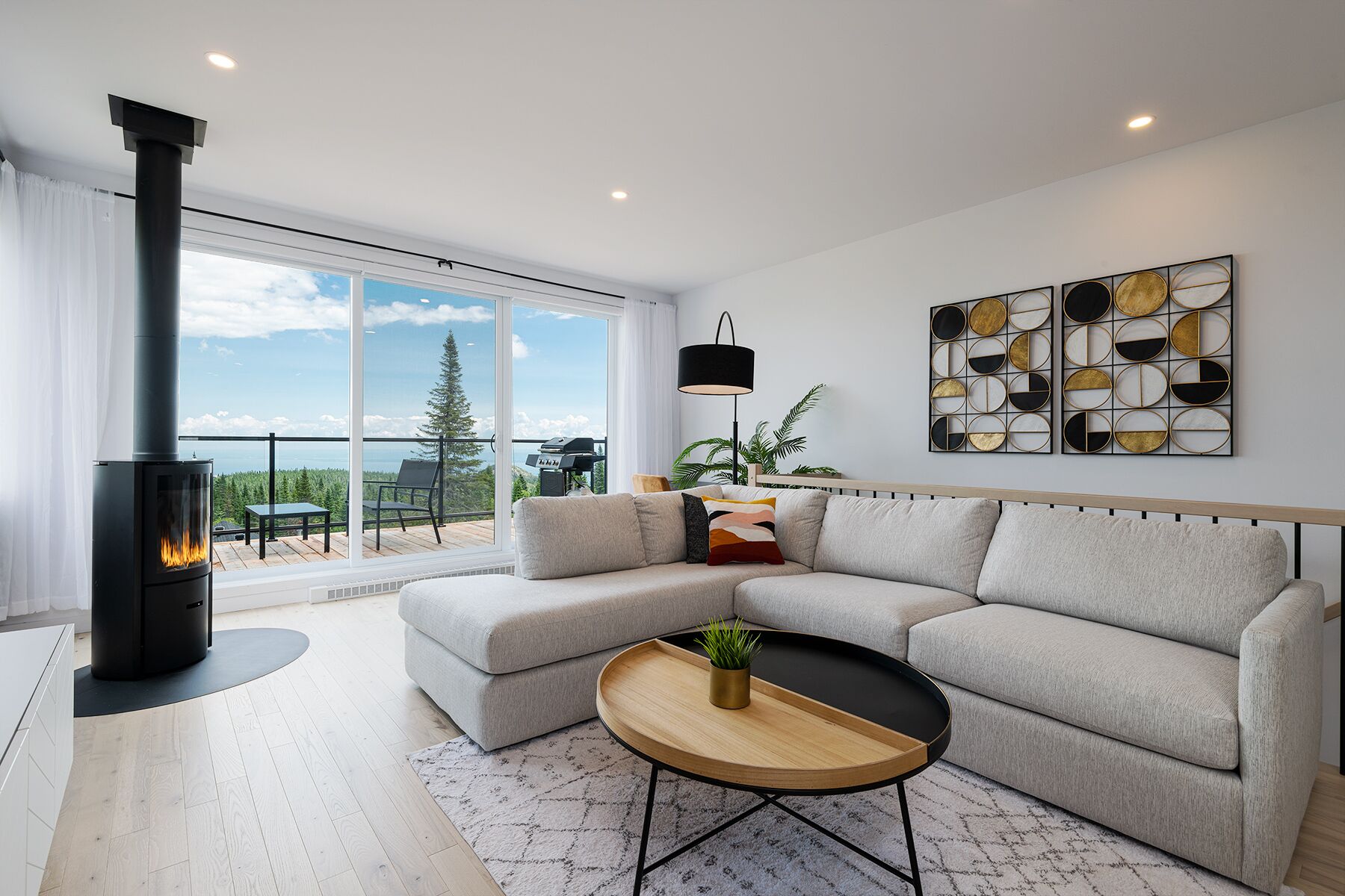 A modern living room with a sectional sofa, a fireplace, and a large window offering a scenic view.