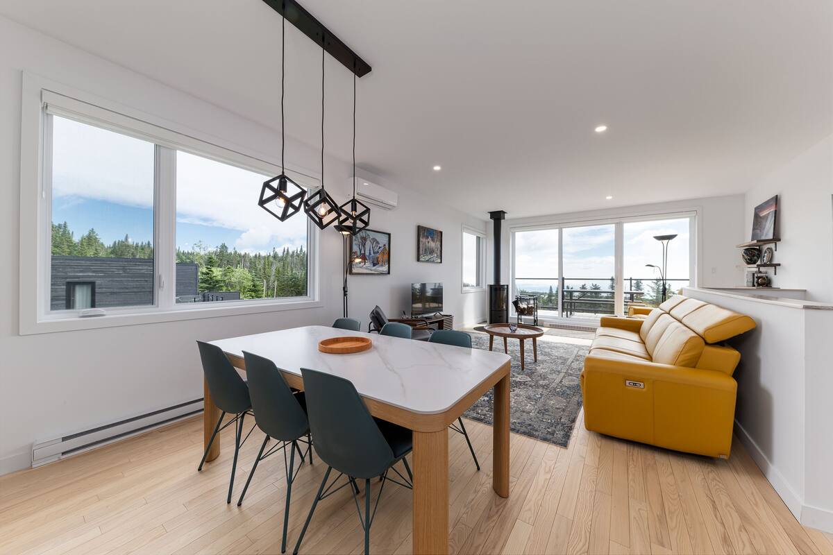 A modern living room with a sofa, dining table, chairs, and a TV.