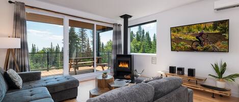 Una sala de estar moderna con chimenea, ventanas amplias y vistas a la montaña.