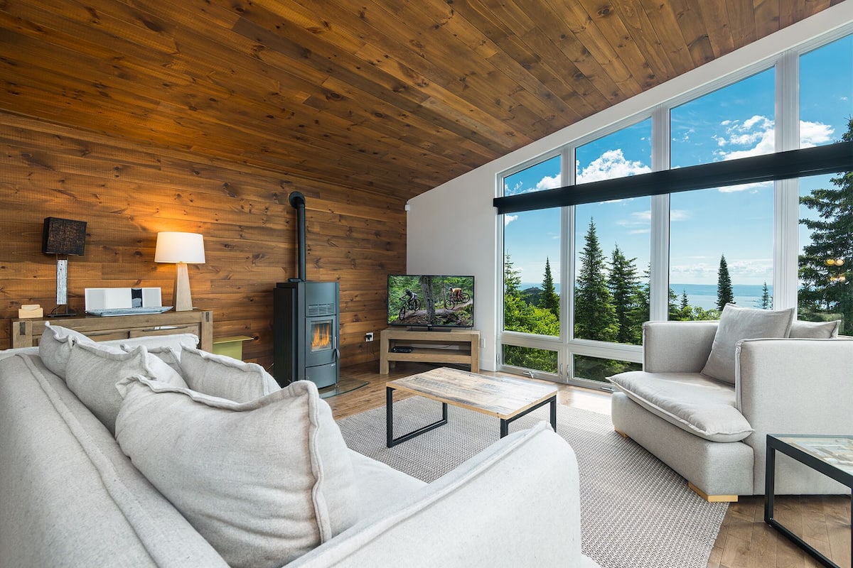 A modern living room with a large window, a fireplace, and a television.