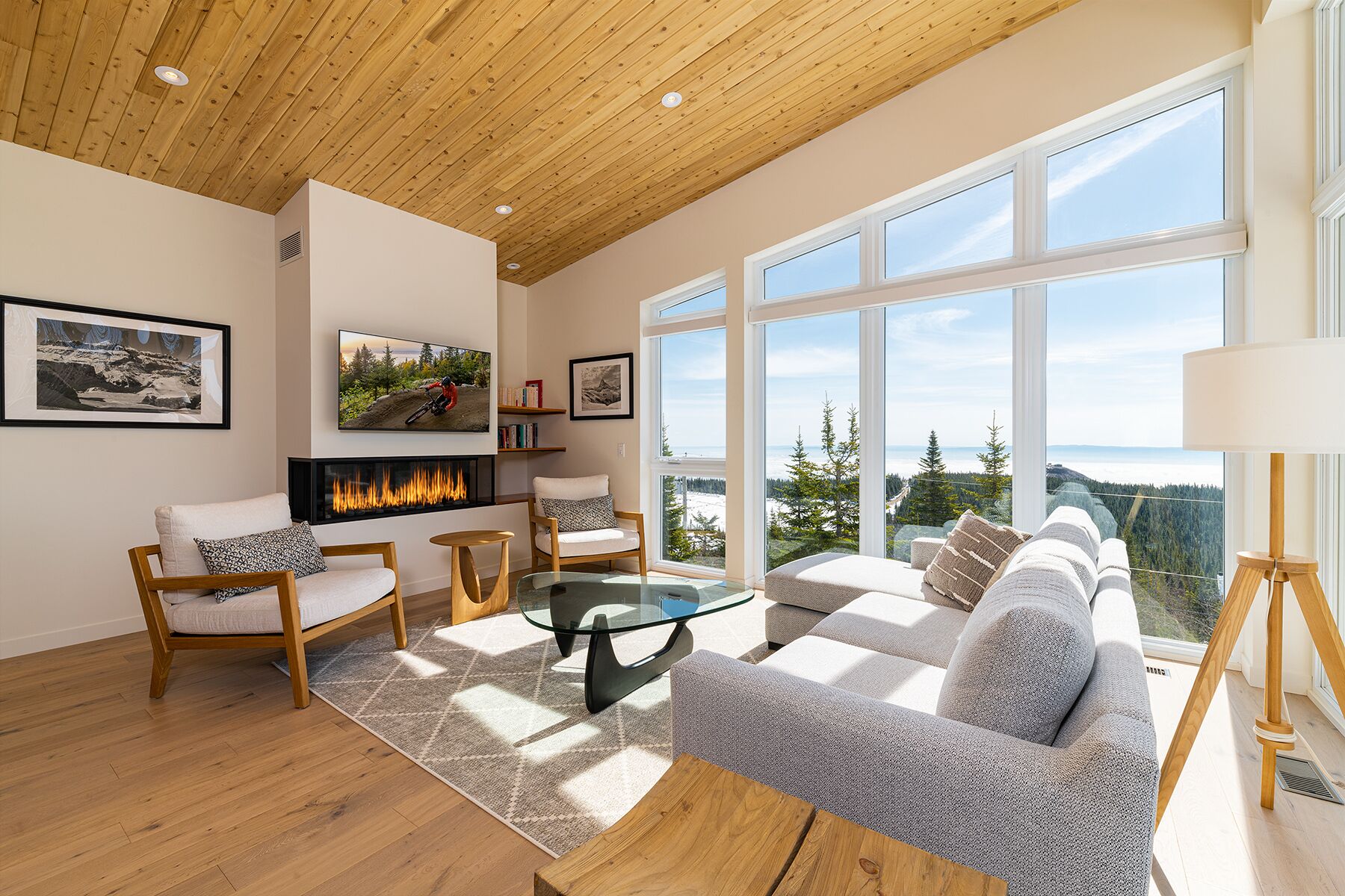 Una sala de estar moderna con chimenea, ventanas amplias y vistas al exterior.
