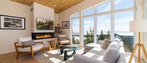 Una sala de estar moderna con chimenea, ventanas amplias y vistas al exterior.