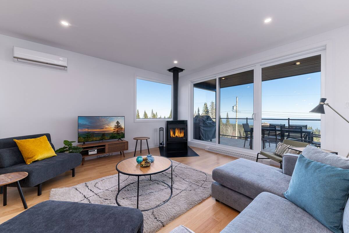 A modern living room with a fireplace, large windows, and a cozy seating area.
