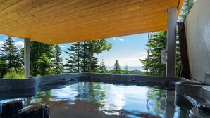 A hot tub with a wooden ceiling and a view of trees and mountains. - Les Chalets Forêt (Petite-Riviere-Saint-Francois)