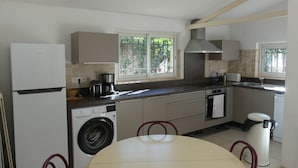 Een kleine keuken met een wasmachine, een koffiezetapparaat en een spoelbak.