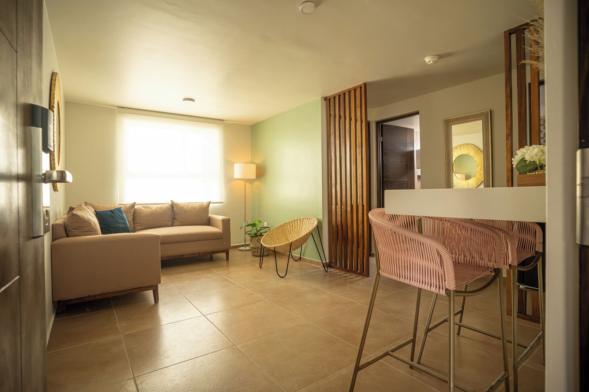 A modern living room with a sofa, a chair, a bar stool, and a lamp.