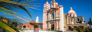 A historic church with a prominent bell tower and a fountain in front.