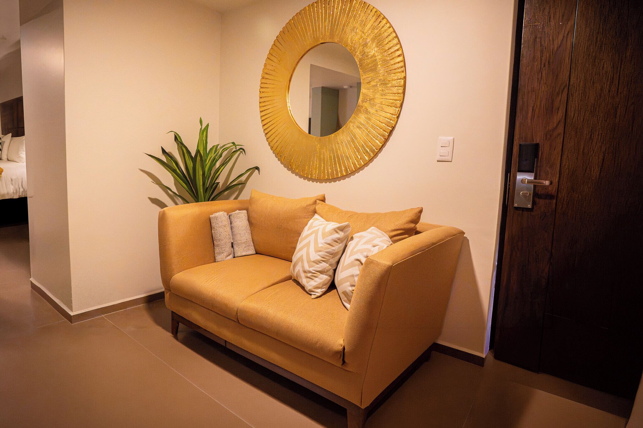 A modern interior with a sofa, a large mirror, and a potted plant.