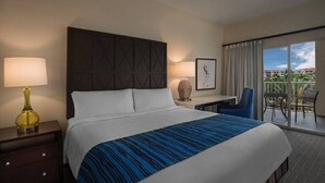 Ein Hotelzimmer mit einem großen Bett, einem Schreibtisch, einem Stuhl und einem Balkon mit Blick.
