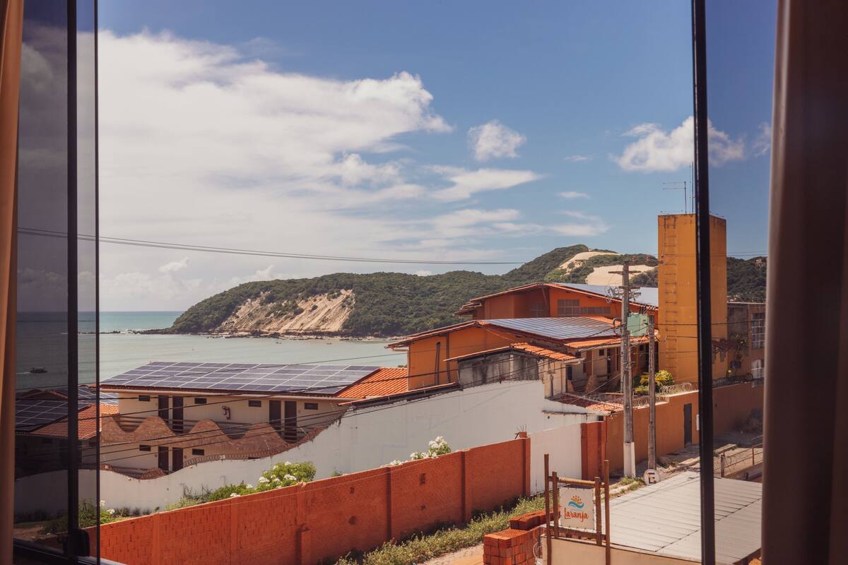 A coastal view with buildings, a beach, and a cliff.