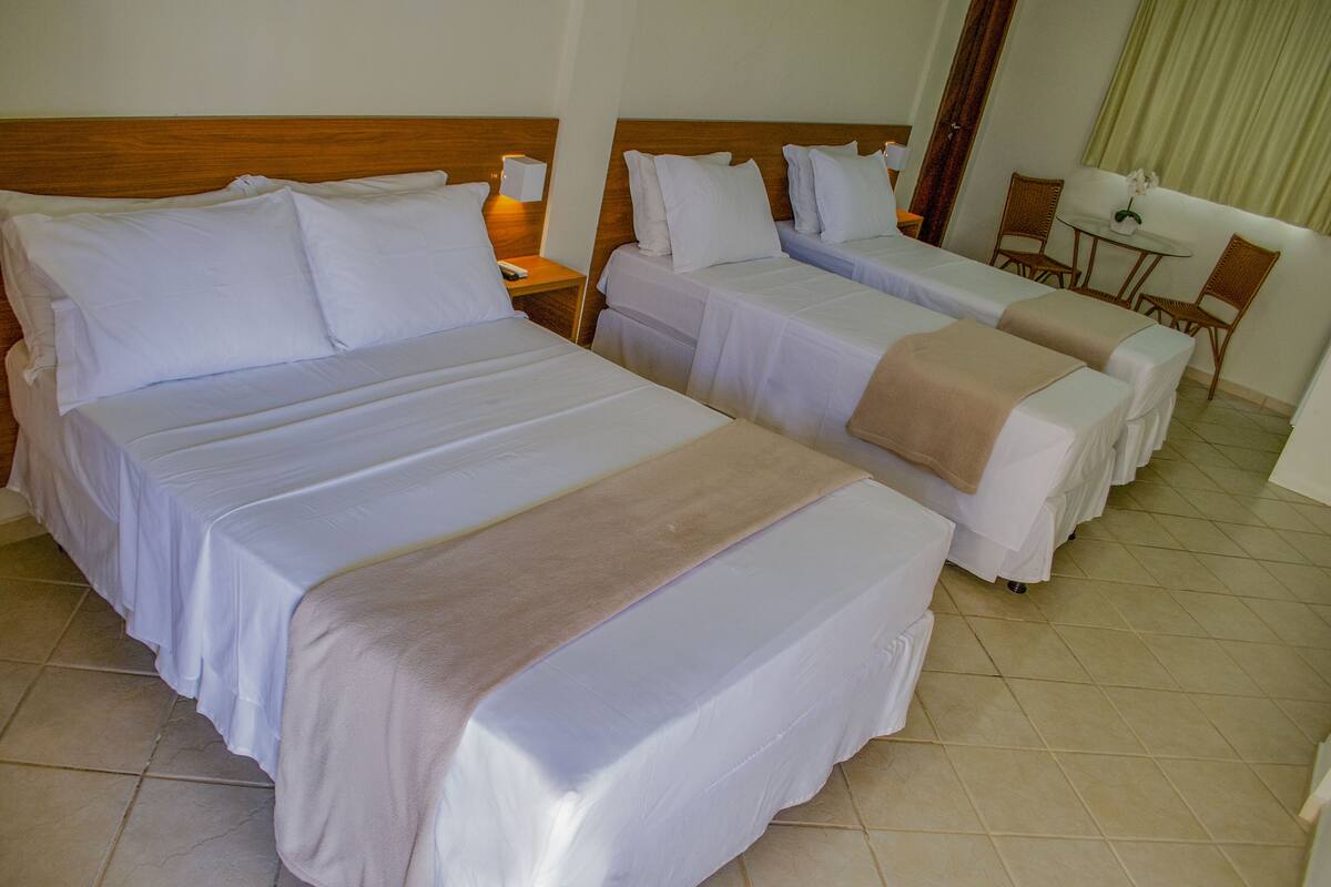 A hotel room with two beds, a small table, and two chairs.