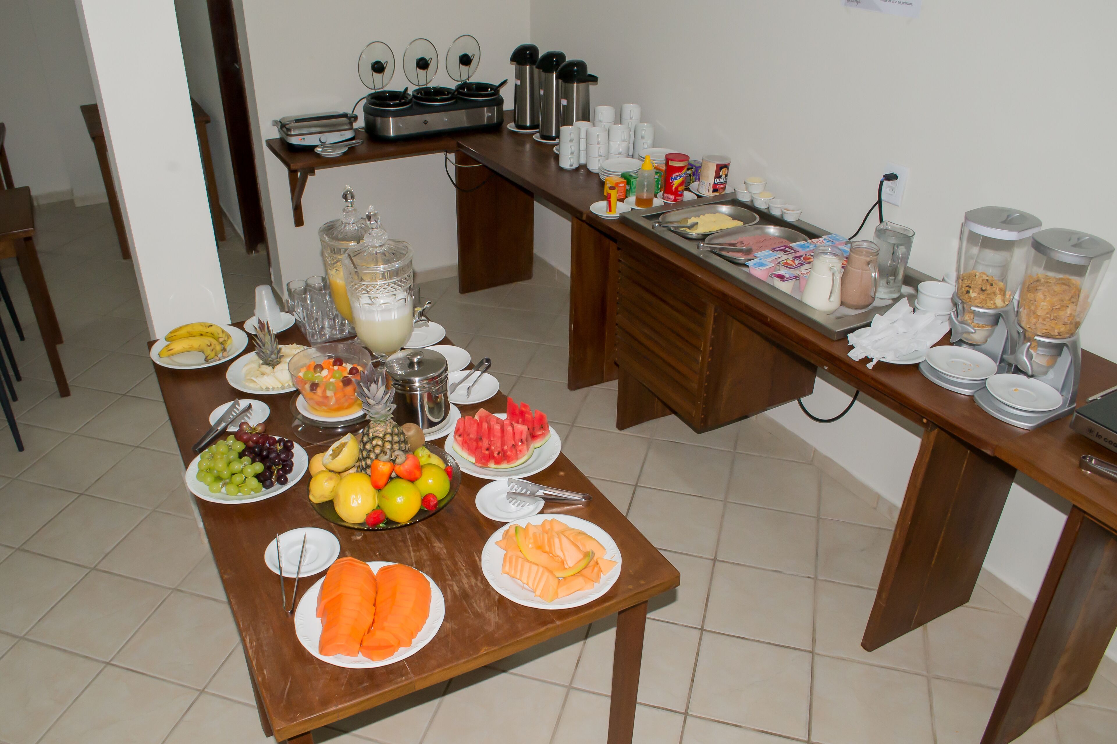A breakfast buffet with various fruits, vegetables, and beverages.