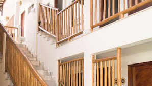 A multi-level wooden staircase with a handrail, leading to a door marked with the number 101. - Pousada Laranja Durigon  (Natal)