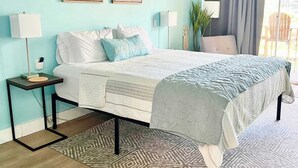A bedroom with a bed, bedside tables, a rug, and artwork on the wall. - The Bungalow, 2nd row from Ocean, Pool/Hot Tub! (Myrtle Beach)