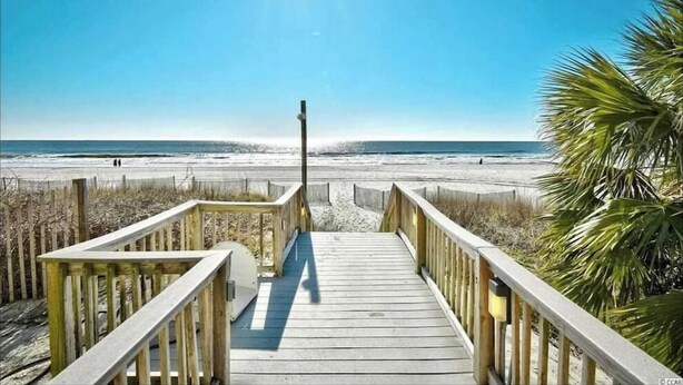 A wooden boardwalk leading to a beach with a clear sky and sun shining. - The Bungalow, 2nd row from Ocean, Pool/Hot Tub! (Myrtle Beach)