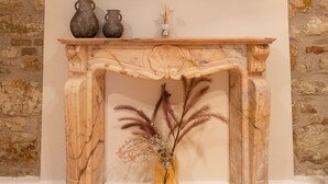 A fireplace with a marble surround, a flat-screen TV mounted above it, and two vases on the mantel.