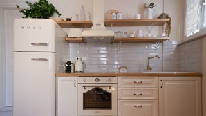 A kitchen with white cabinetry, a white refrigerator, a stove, and a sink.