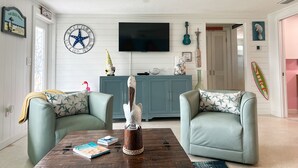 A living room with two green armchairs, a wooden coffee table, a TV, and a blue cabinet. - Beautiful Home,ON THE KEY🏝️ FreeBikes,BeachChairs,FirePit,Kayaks,Newly Renovated  (Englewood)