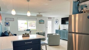 A modern kitchen with a central island, a refrigerator, and a dining area with a sofa and a chair. - Beautiful Home,ON THE KEY🏝️ FreeBikes,BeachChairs,FirePit,Kayaks,Newly Renovated  (Englewood)
