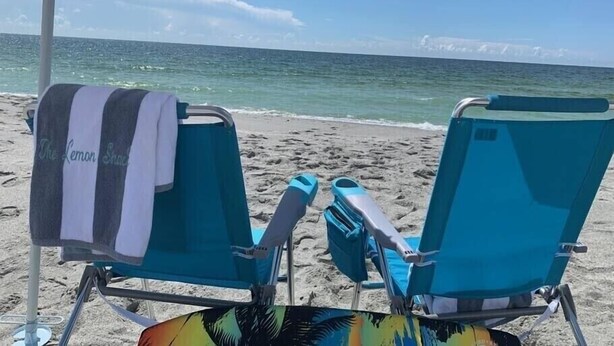 Two beach chairs with towels, a beach umbrella, and a view of the ocean. - Beautiful Home,ON THE KEY🏝️ FreeBikes,BeachChairs,FirePit,Kayaks,Newly Renovated  (Englewood)