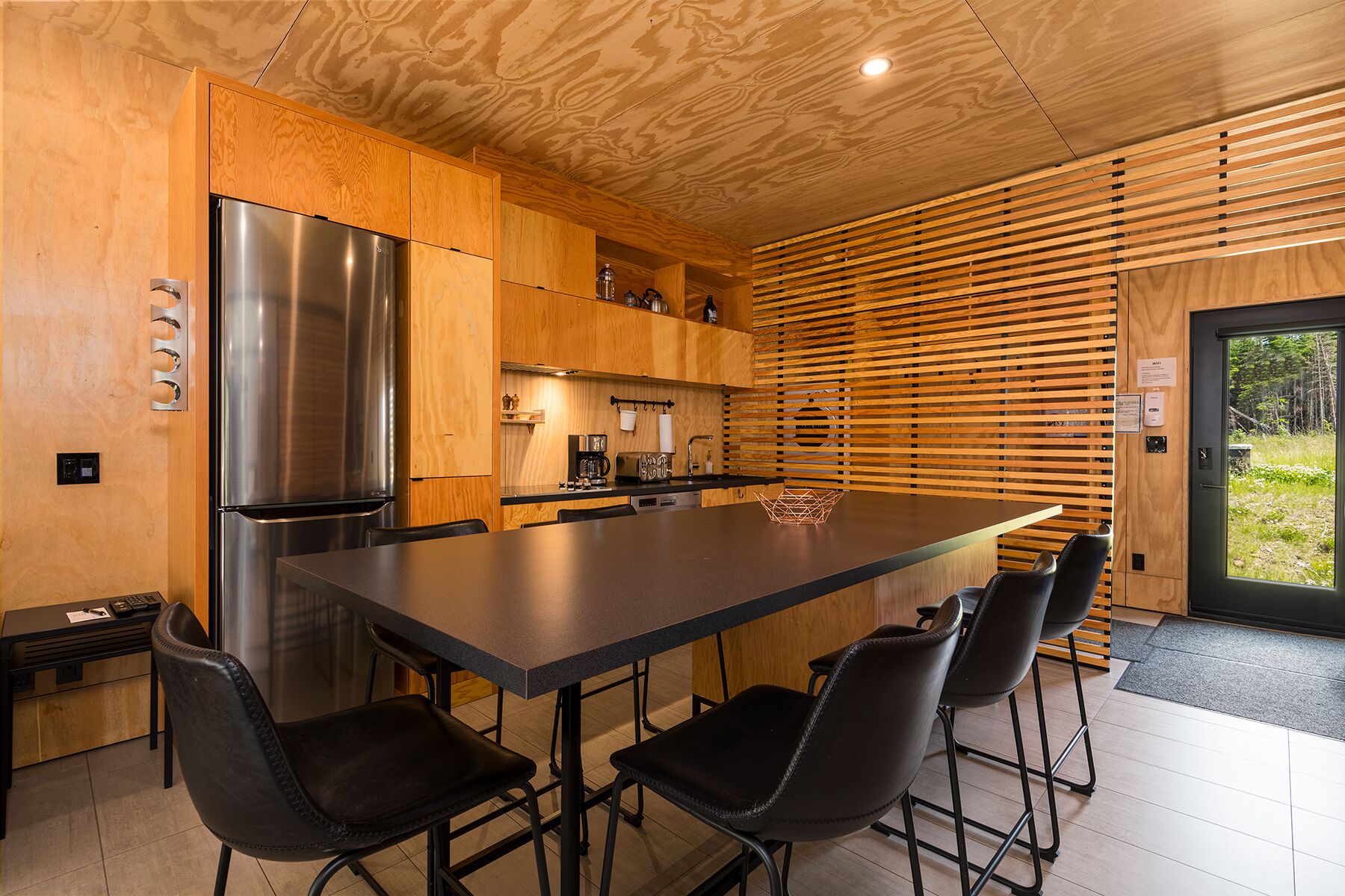 A modern kitchen with a large island, stainless steel appliances, and wooden cabinetry.