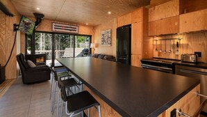 A modern kitchen with a large island, wooden cabinetry, and a built-in stove. - Les Refuges (Petite-Riviere-Saint-Francois)