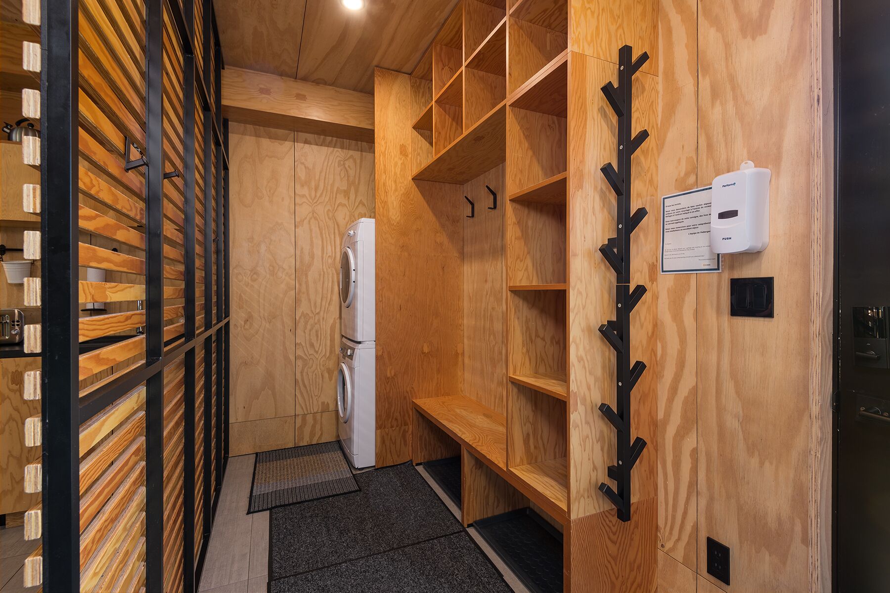 Una lavanderia con scaffali in legno, una lavatrice e un dispenser per carta.