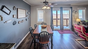 A dining area with a wooden table, chairs, and a ceiling fan.