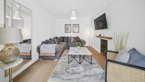 A modern living room with a sectional sofa, a coffee table, a floor lamp, and a fireplace.
