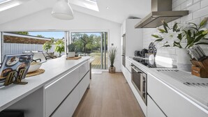 A modern kitchen with a central island, a skylight, and a view of the backyard.