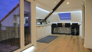 Una cocina moderna con tragaluces, piso de madera y zona de comedor con taburetes de bar.