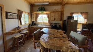 Een landelijke keuken met houten kasten, een centraal eiland en een eethoek met houten stoelen.