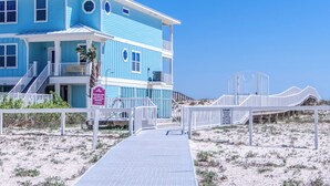 Une maison à deux étages située en bord de mer, dotée d’un balcon, d’une véranda et d’une plage de sable.