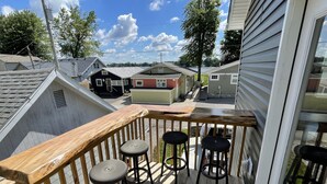 A wooden deck with a railing and three round tables.