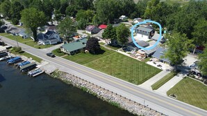 An aerial view of a residential area with houses, a road, and a dock with boats.
