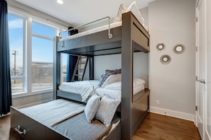 Habitación con literas, un escritorio, una ventana con cortinas y adornos en la pared.